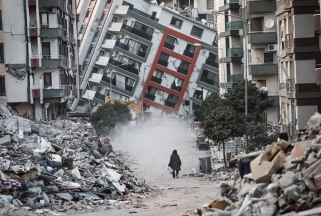 Una mujer pasa junto a edificios en ruinas, tras los terremotos de Turquía. EFE / Sedat Suna