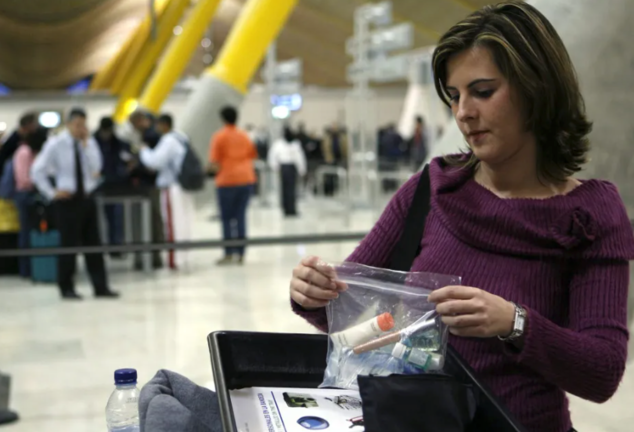 Una mujer deposita una bolsa en una bandeja antes de pasar por el control de seguridad del aeropuerto Madrid-Barajas. EFE / Emilio Naranjo