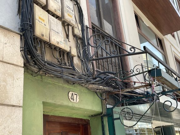 Tendido de cables en la fachada de un edificio de Torrelavega. / Alerta