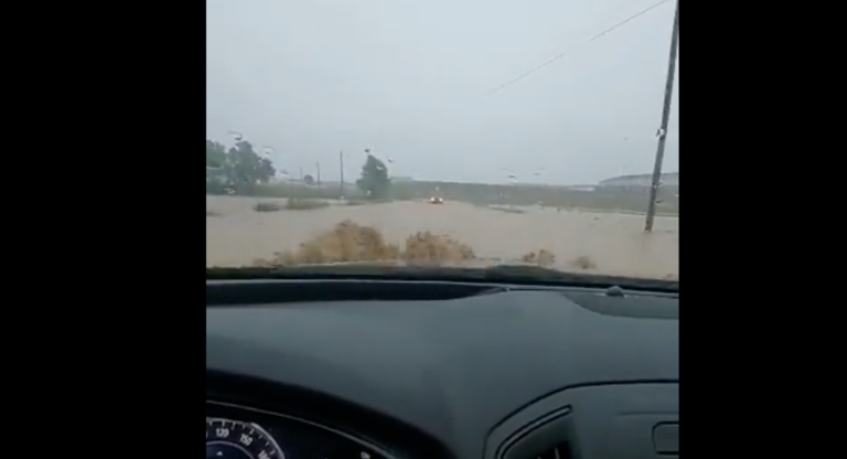 Un coche circula por una carretera anegada por las lluvias.