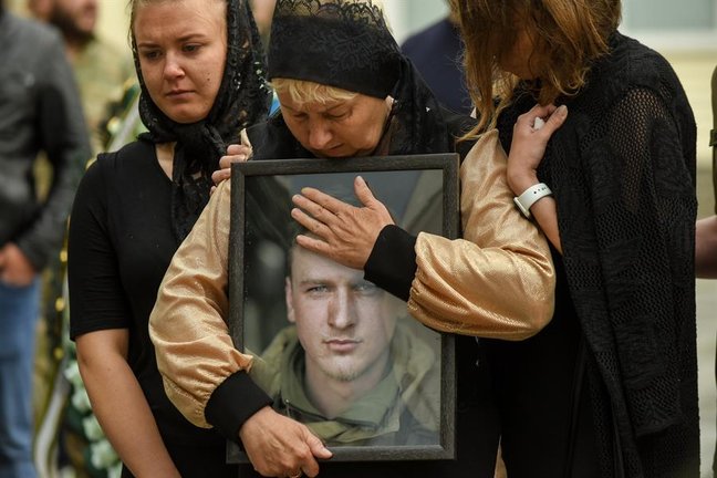 La madre de un soldado ucraniano abraza el retrato de su hijo durante su ceremonia fúnebre. EFE/ Oleg Petrasyuk