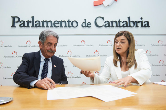 La presidenta del Partido Popular de Cantabria, María José Sáenz de Buruaga, firma con el secretario general del PRC, Miguel Ángel Revilla. César Ortiz / Europa Press