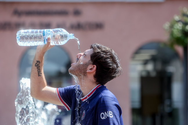 Un joven se tira una botella de agua por encima para combatir el calor del verano. / Ricardo Rubio