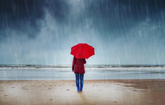 Una persona en la playa con su paraguas.
