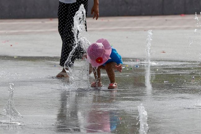 Una niña se refresca en una fuente de chorros. / J.C. Hidalgo
