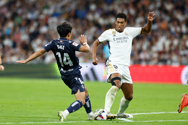 El centrocampista japonés de la Real Sociedad, Take Kubo (i), disputa el balón ante el delantero inglés del Real Madrid, Jude Bellingham. / Rodrigo Jiménez.