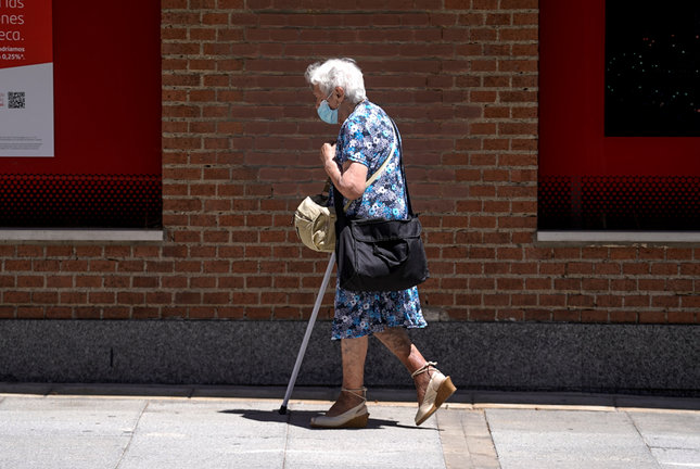 Una anciana con mascarilla camina por la calle ayudada de una muleta, a 27 de julio de 2021, en Madrid, (España). La Seguridad Social destinó en el presente mes de julio la cifra récord de 10.202,29 millones de euros al pago de pensiones contributivas, lo que supone un 3,23% más que en el mismo mes de 2020. / ALERTA