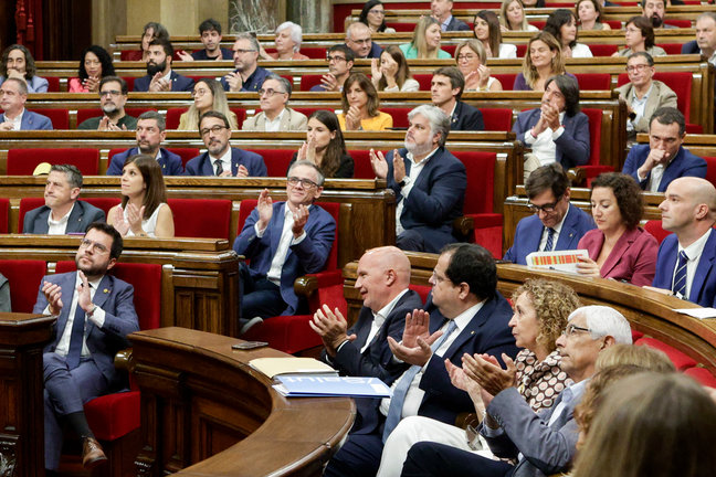 El presidente de la Generalitat, Pere Aragonès (i), junto a los diputados de los partidos independentistas aplauden el resultado de la votación durante el pleno del Parlament. /Quique García