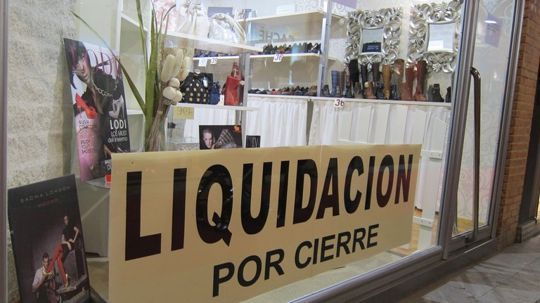 Una tienda cuelga en su escaparate un cartel de 'liquidación por cierre'. / EP