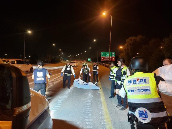 Las autoridades israelíes recogiendo un cadáver de la carretera.