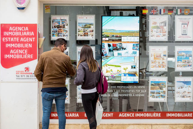 Una pareja se detiene a observar las ventas de viviendas anunciadas en una inmobiliaria. EFE/ David Arquimbau Sintes
