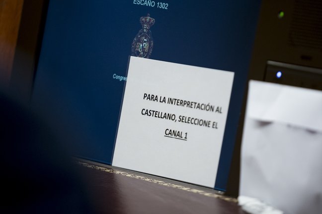 Un cartel para el uso de pinganillos en el Congreso de los Diputados, en Madrid. EP / A. Pérez Meca