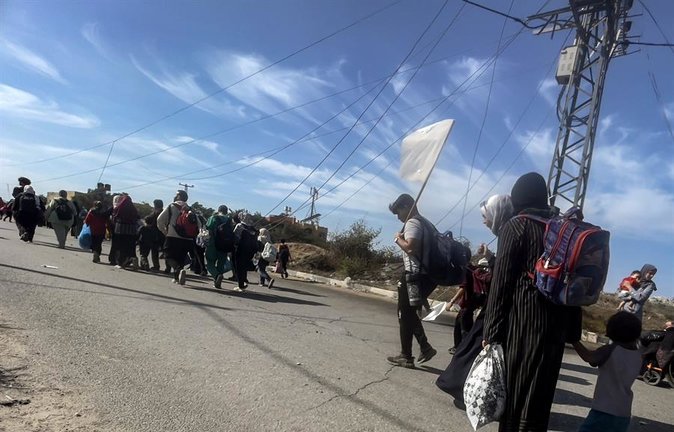 Palestinos, con una bandera blanca improvisada, parten hacia el sur de la Franja de Gaza a través de un puesto de control del ejército israelí. EFE /  MOHAMMED SABRE