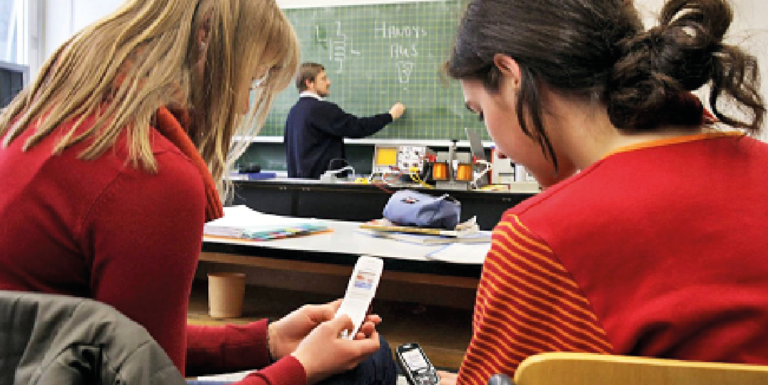 Dos estudiantes usan sus teléfonos móviles durante una clase. /  Marcus Fuerer