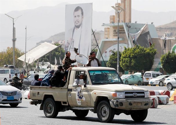 Simpatizantes hutíes viajan en un vehículo pasando junto a una pancarta que representa al máximo líder hutí, Abdul-Malik al-Houthi, en una calle de Saná, Yemen. EFE / Yahya Arhab