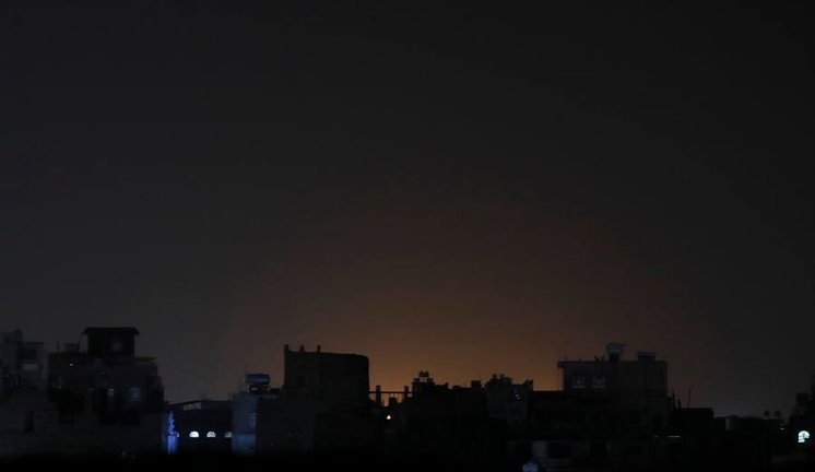 Vista general del resplandor producto de ataques aéreos, detrás de un conjunto de edificios, en Saná (Yemen). EFE/Yahya Arhab