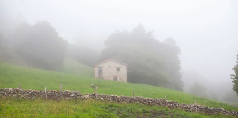 Casa rural en prado con bruma. Cantabria, España.