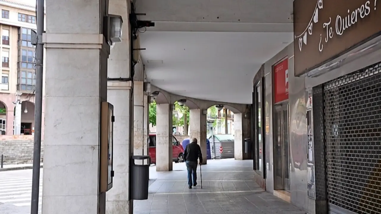 Un hombre de avanzada edad camina bajo los soportales junto a la plaza Mayor de Torrelavega. / S.D.