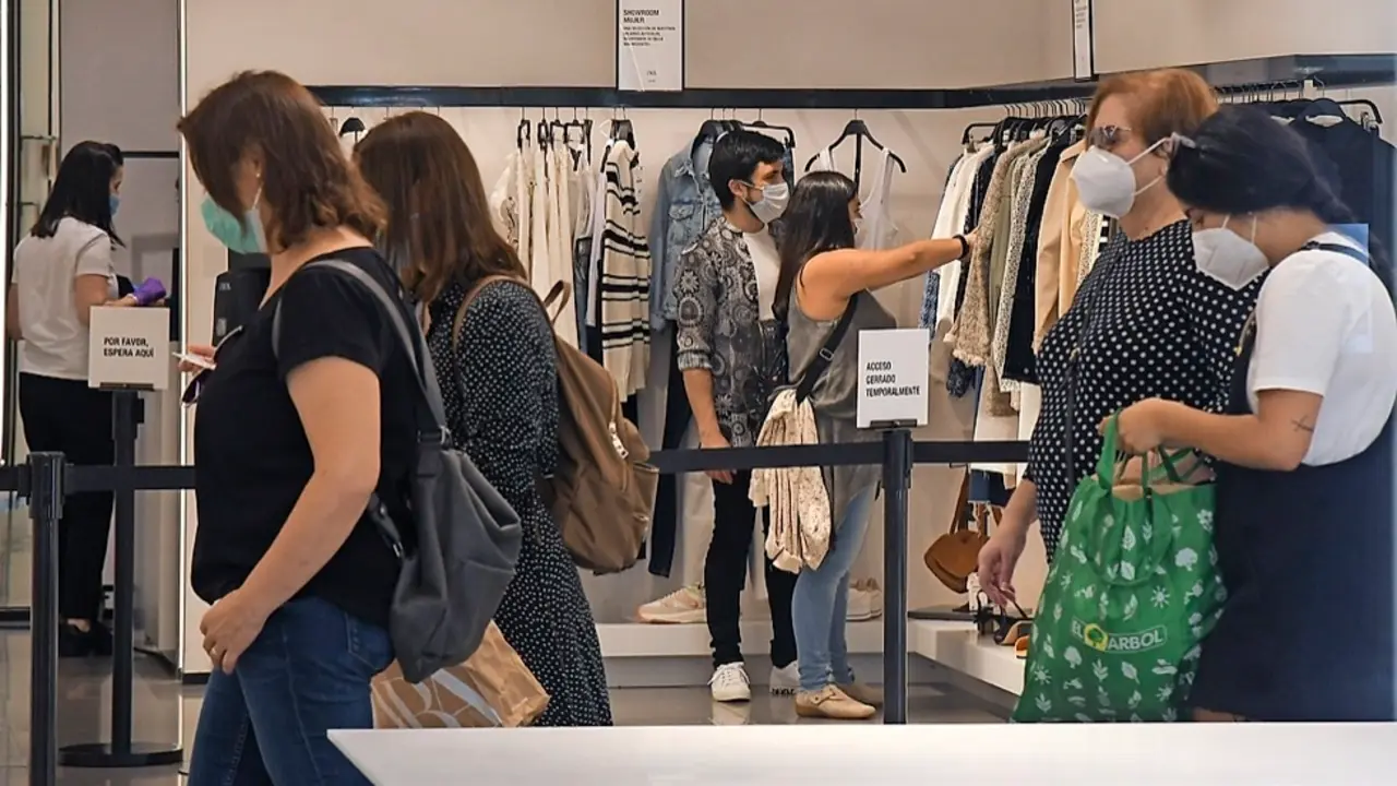 Varias personas comprando en una tienda de ropa. / Hardy