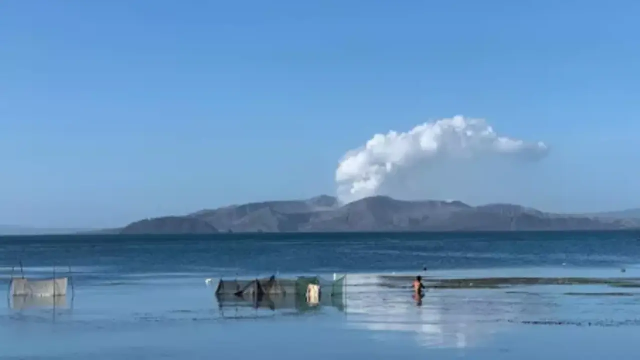Un hombre camina por las aguas del lago Taal mientras las cenizas y el vapor se elevan desde el cr&aacute;ter del volc&aacute;n Taal. - Girlie Linao / dpa - Archivo