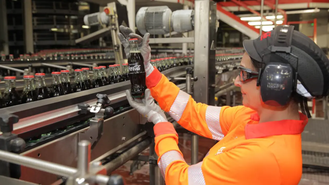 Una operario de Coca-Cola sostiene un envase en la planta de producci&oacute;n.