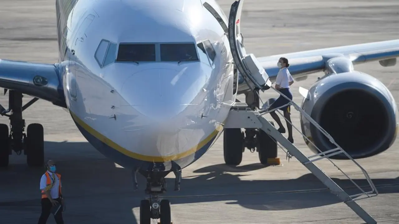 Una azafata sube a bordo de un avi&oacute;n de Ryanair, con destino Valencia, que ha sido el primero en despegar, este martes, del aeropuerto Seve Ballesteros en Malia&ntilde;o (Cantabria), tras tres meses sin actividad en el aeropuerto debido al coronavirus. EFE/Pedro Puente Hoyos