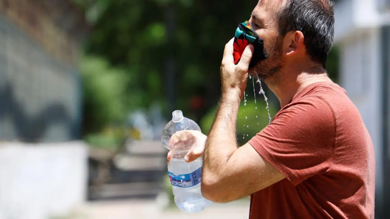 Un hombre refresca su mascarilla ante las altas temperaturas. / EFE