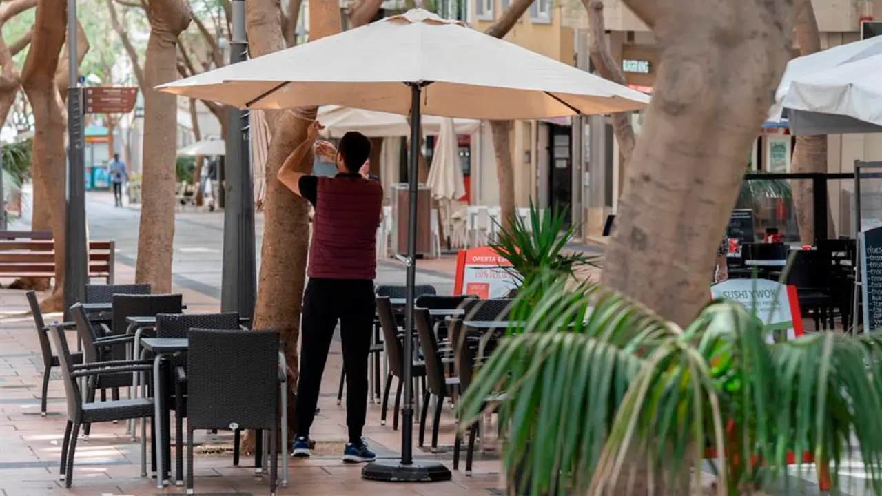Un camarero coloca una sombrilla en una terraza de un bar. EFE/Miguel Barreto/Archivo