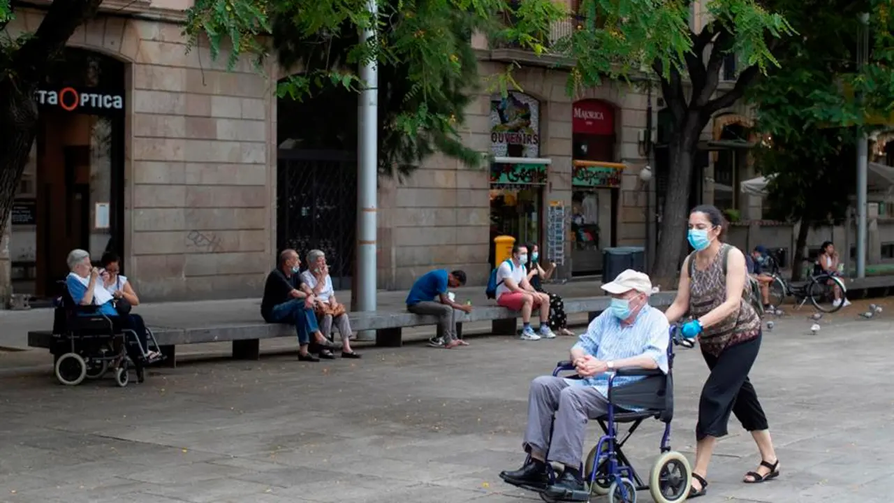 Una mujer empuja la silla de un se&ntilde;or mayor en el centro de Barcelona. EFE/ Marta P&eacute;rez/Archivo