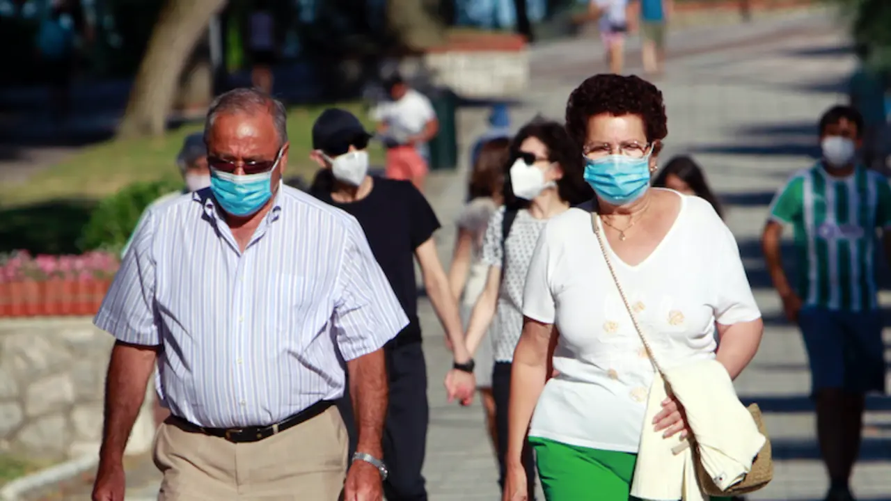 Dos personas caminan con su mascarilla en el paseo de la playa del Sardinero. / J. R.