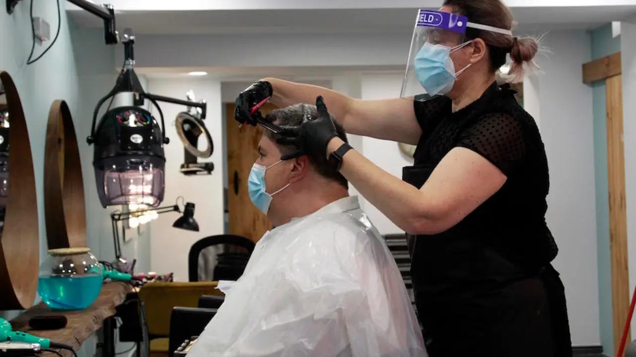 Una persona con mascarilla le corta el pelo en una peluquer&iacute;a de Santander. / J.R.