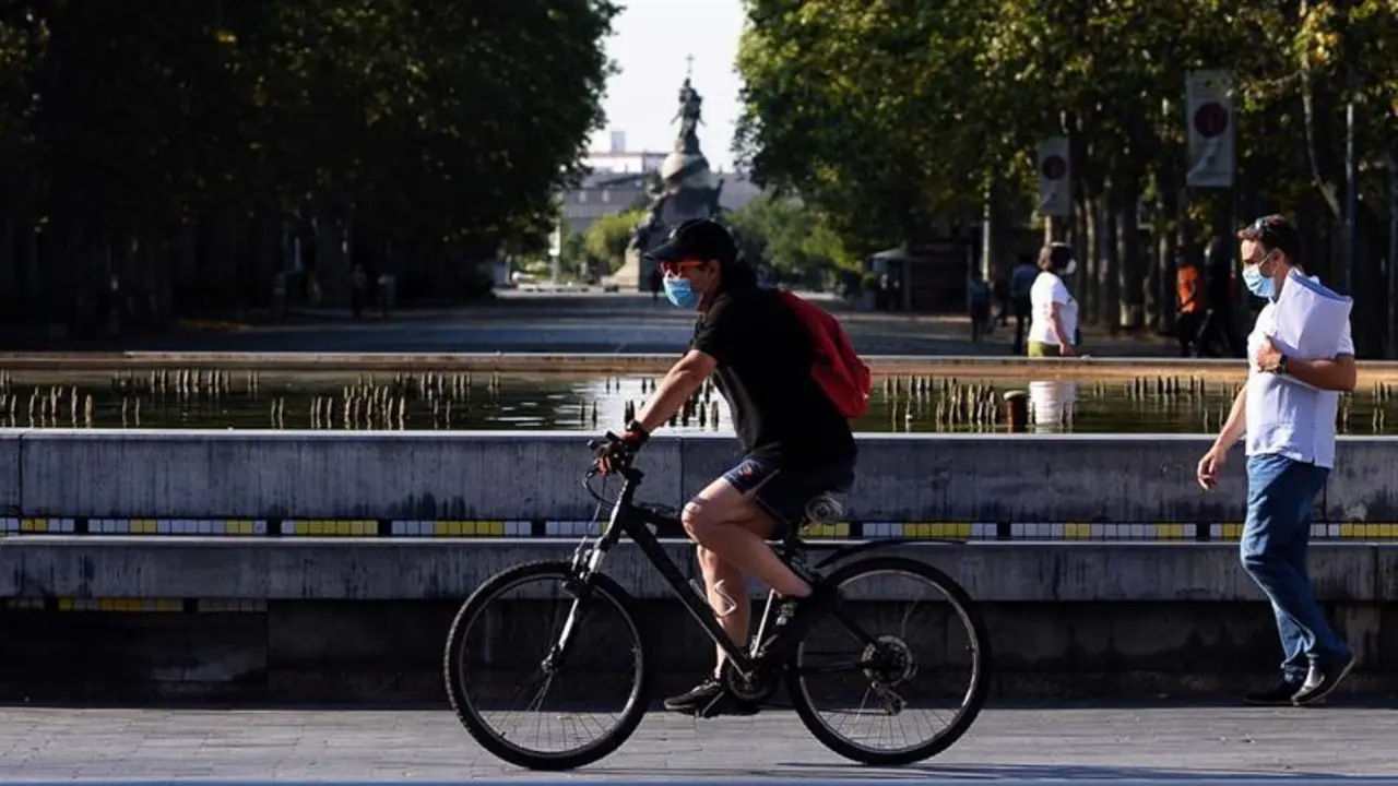 Un hombre circula en bicicleta y con mascarilla por el centro de la ciudad de Valladolid donde este viernes las temperaturas superar&aacute;n los 35 grados cent&iacute;grados. EFE/ Nacho Gallego