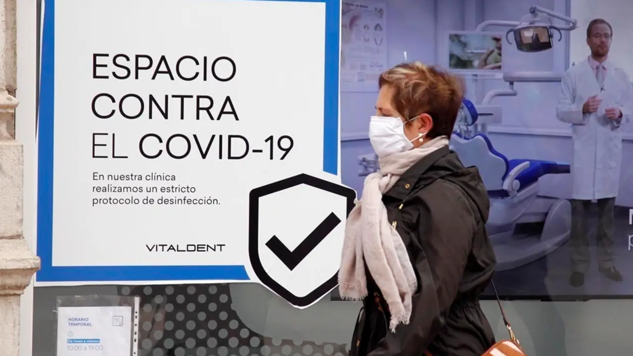 Una mujer pasa por delante de un cartel de una clinica dentista en Santander. / J.R.