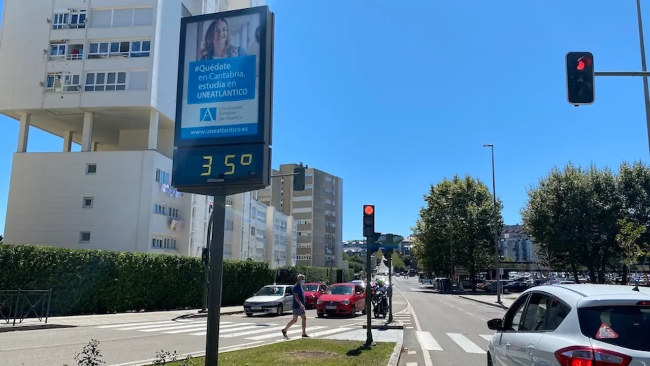 Un hombre pasea al lado de una se&ntilde;al que marca 35 grados en una jornada de altas temperaturas en la regi&oacute;n. / hardy