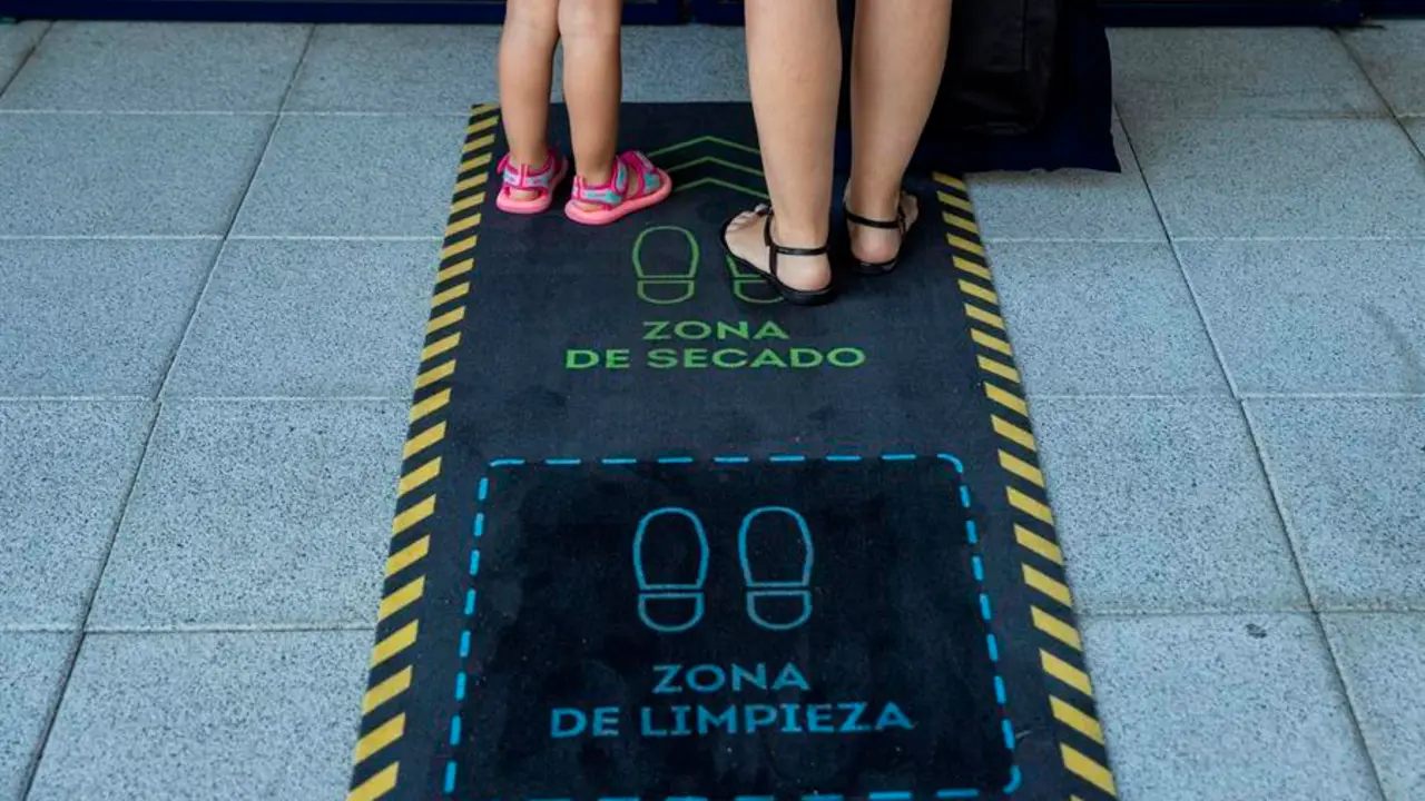 Una madre y su hija se limpian los zapatos durante la reapertura de una escuela infantil en Madrid. EFE/ Rodrigo Jim&eacute;nez/Archivo