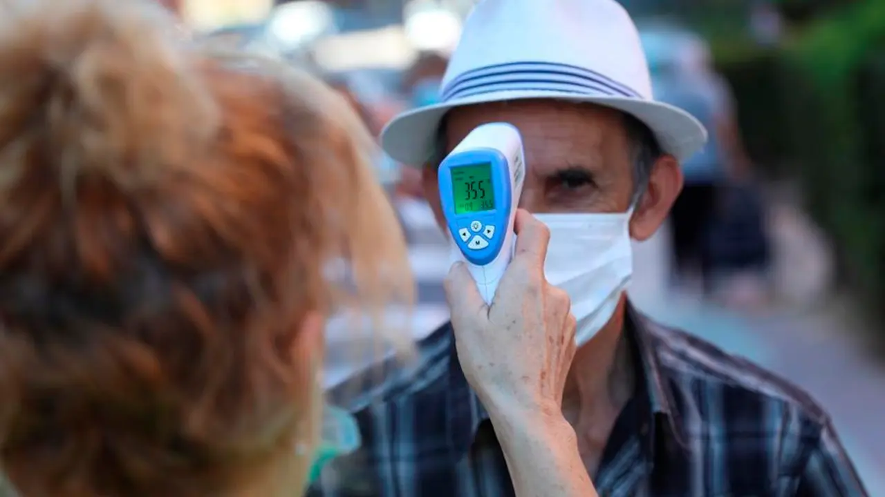 Una voluntaria de una asociaci&oacute;n de mayores toma la temperatura a un anciano. EFE/Rodrigo Jim&eacute;nez/Archivo