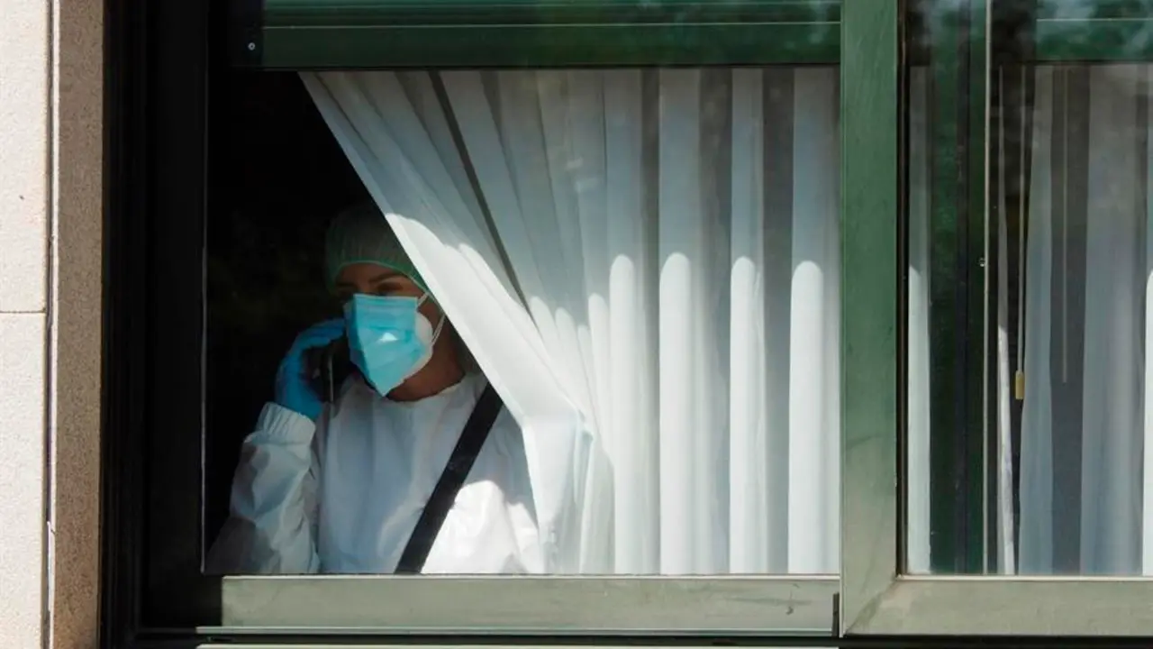 Una trabajadora sanitaria habla por tel&eacute;fono este s&aacute;bado desde el interior de la residencia de O Inicio (Lugo). EFE/Eliseo Trigo/Archivo