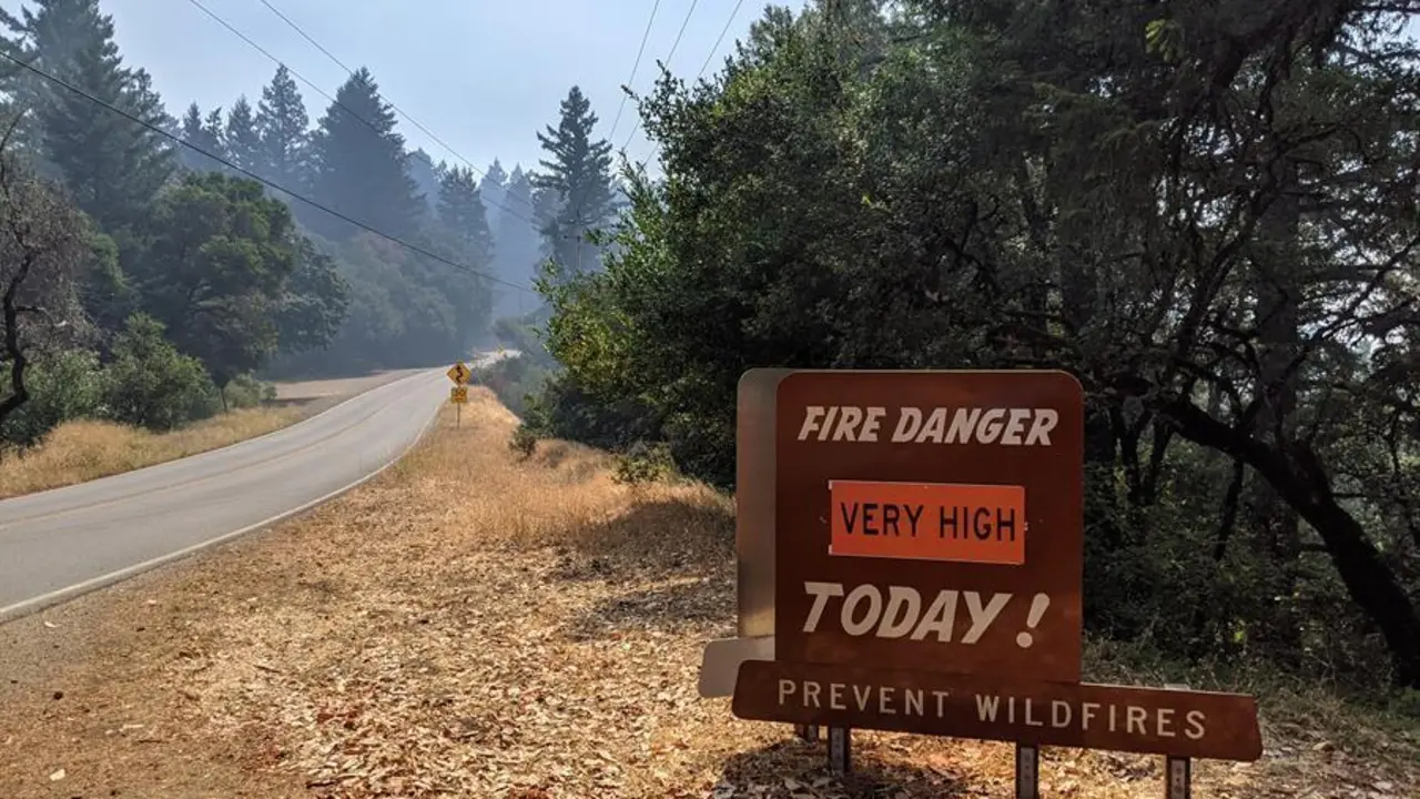 Fotograf&iacute;a de un cartel que indica peligro de incendio puesto frente a secuoyas en la ruta entre Pescadero y Santa Cruz hoy, en California (EEUU). EFE/Marc Arcas