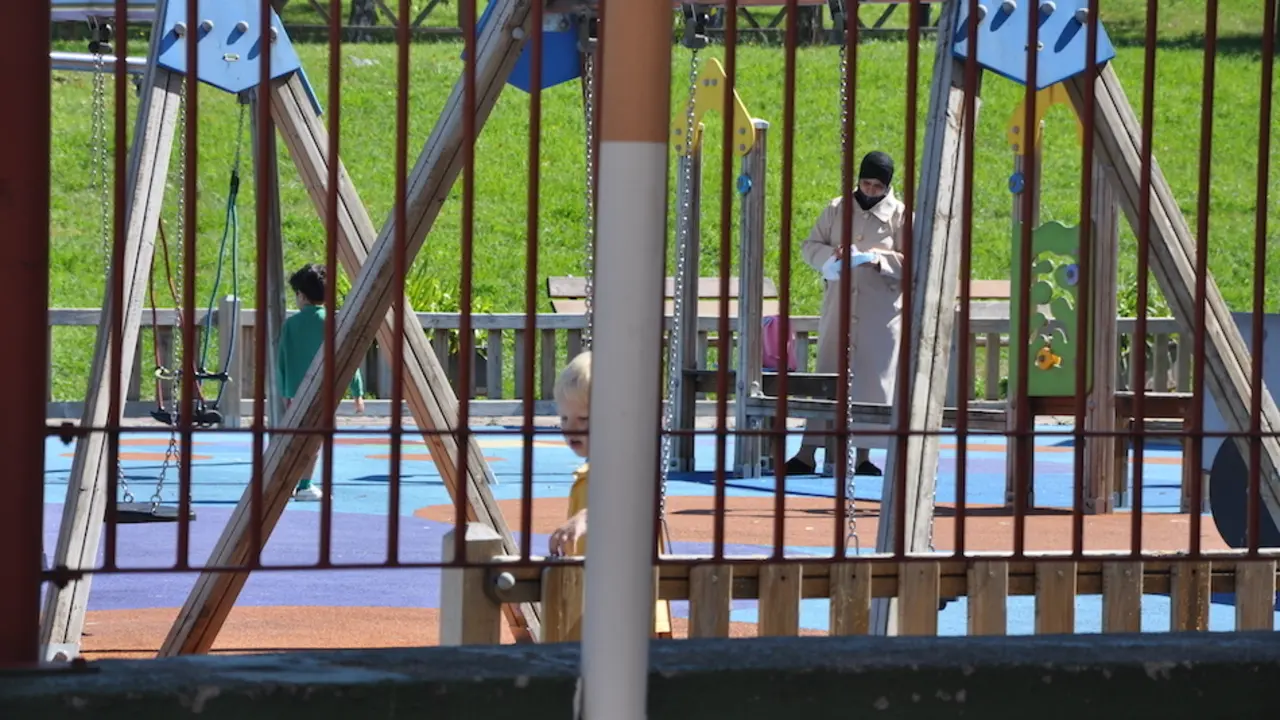 Una madre juega con su hijo en el parque junto al CEIP Jos&eacute; Mar&iacute;a Pereda en Torrelavega. / S.D.