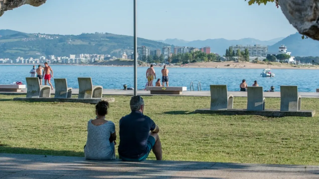 Dos personas sentados junto al paseo en Santo&ntilde;a, Cantabria. / Reguera