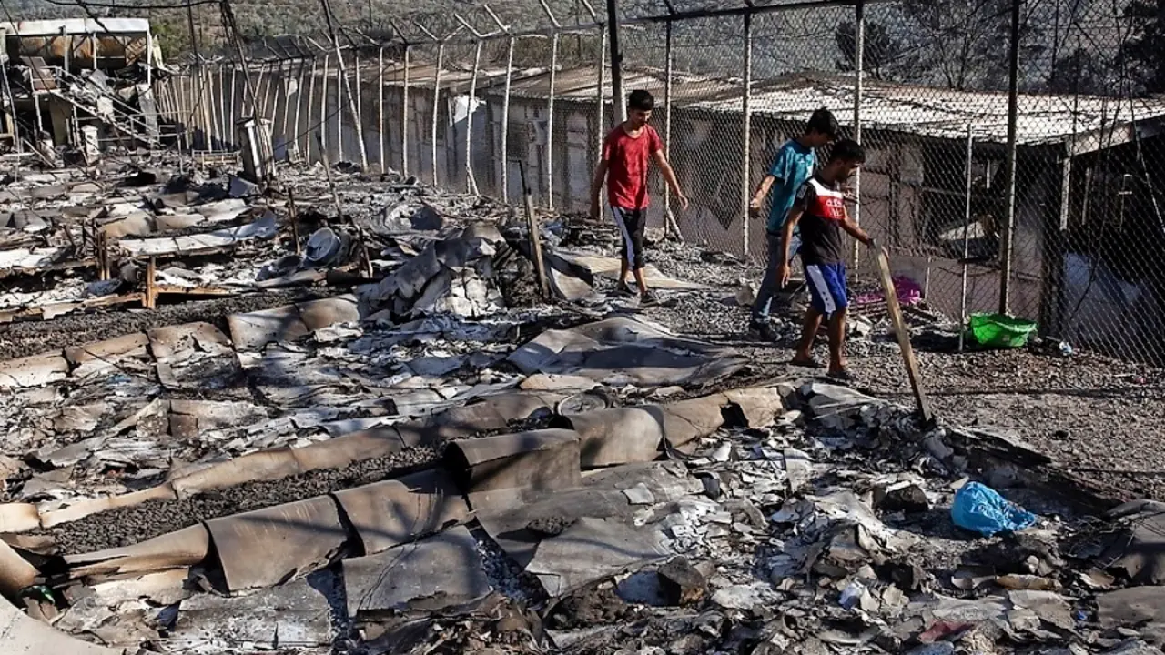 Tres ni&ntilde;os se abren paso entre las cenizas y los escombros del que ha sido su alojamiento y el de otros 13.000 migrantes en Lesbos. / efe