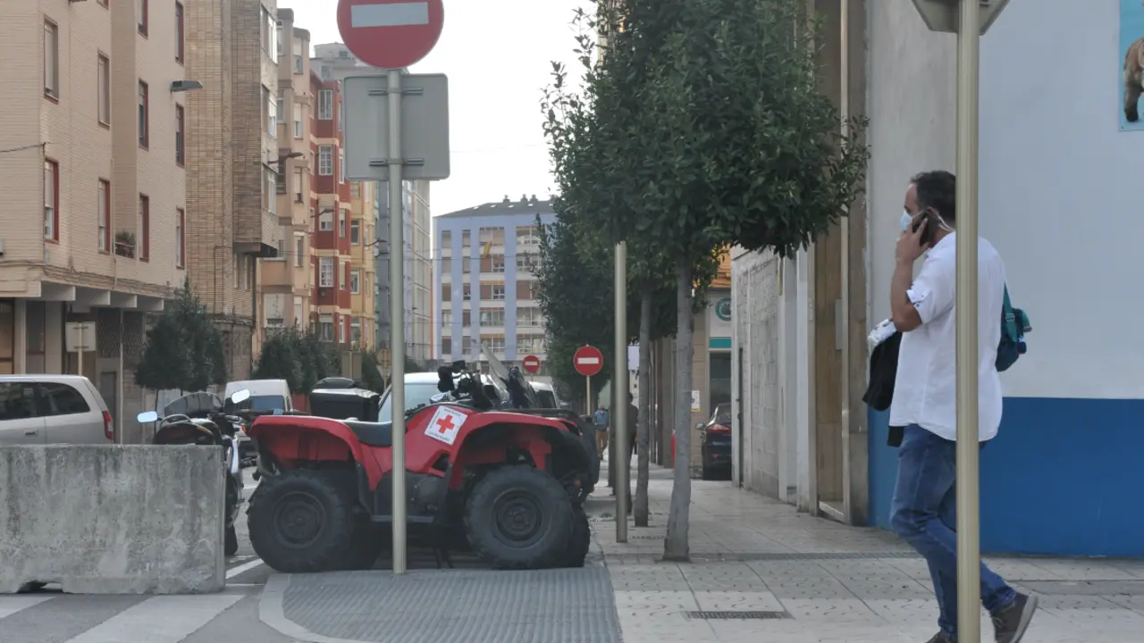 Una persona pasa delante de la barrera en la entrada del barrio de La Inmobiliaria en Torrelavega. / S.D.