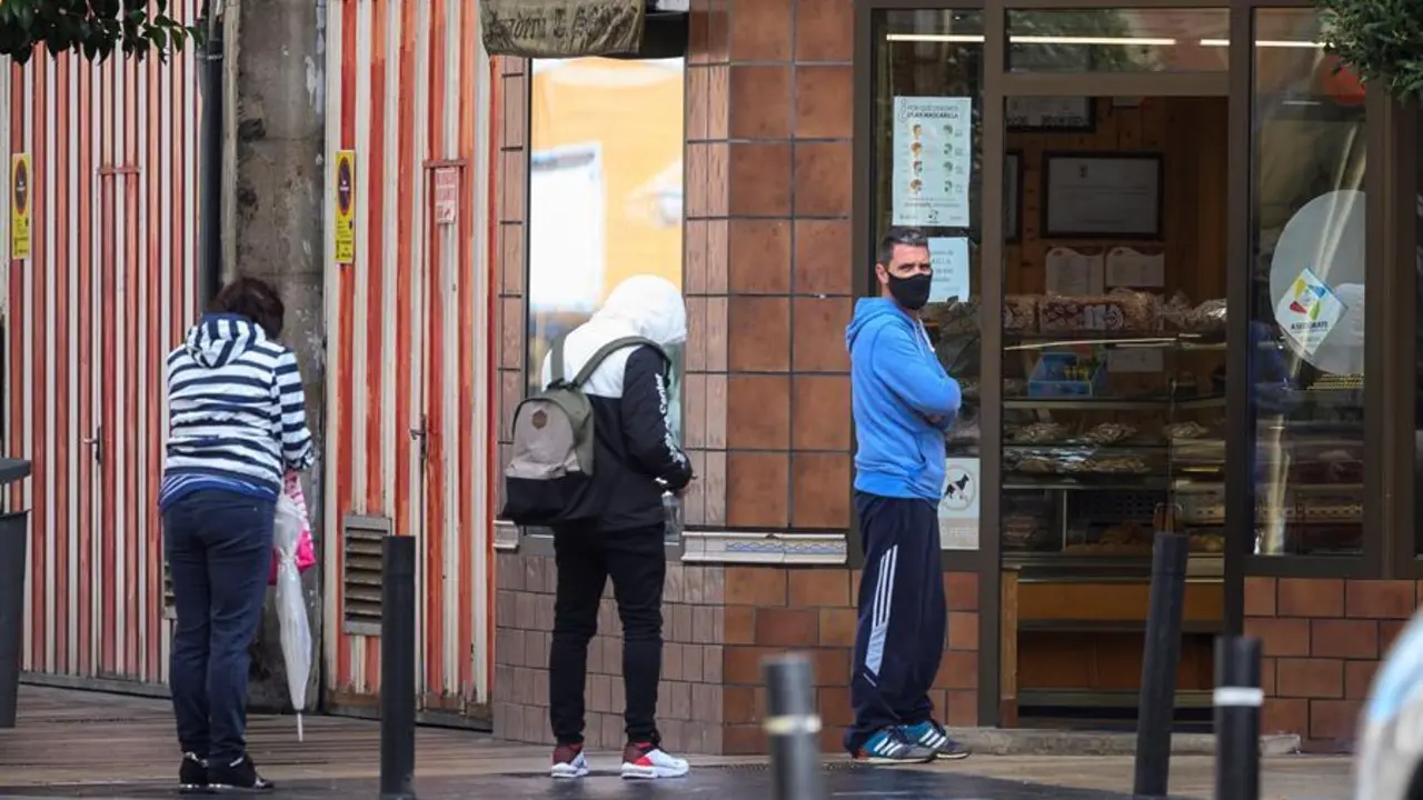 Varias personas esperan en la entrada de la Panader&iacute;a Sordo en el barrio de La Inmobiliaria en Torrelavega. / Pedro Puente Hoyos