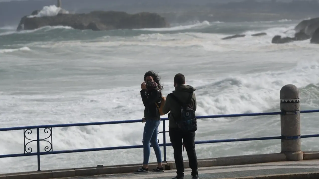 Dos j&oacute;venes se fotograf&iacute;an en con el mar cantabrico de fondo en la playa del Sardinero. / HARDY