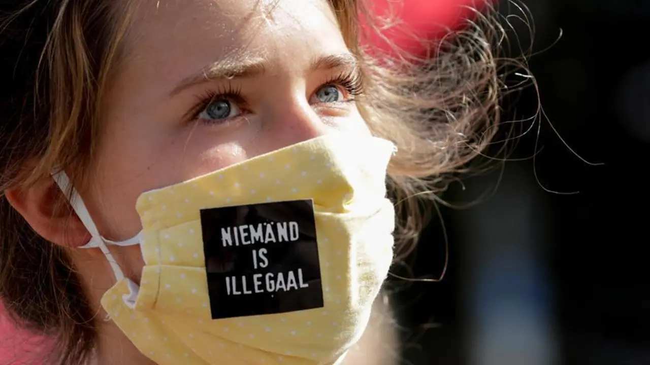 Activista de derechos humanos con `` nadie es ilegal '' en su m&aacute;scara protesta frente al Parlamento Europeo.