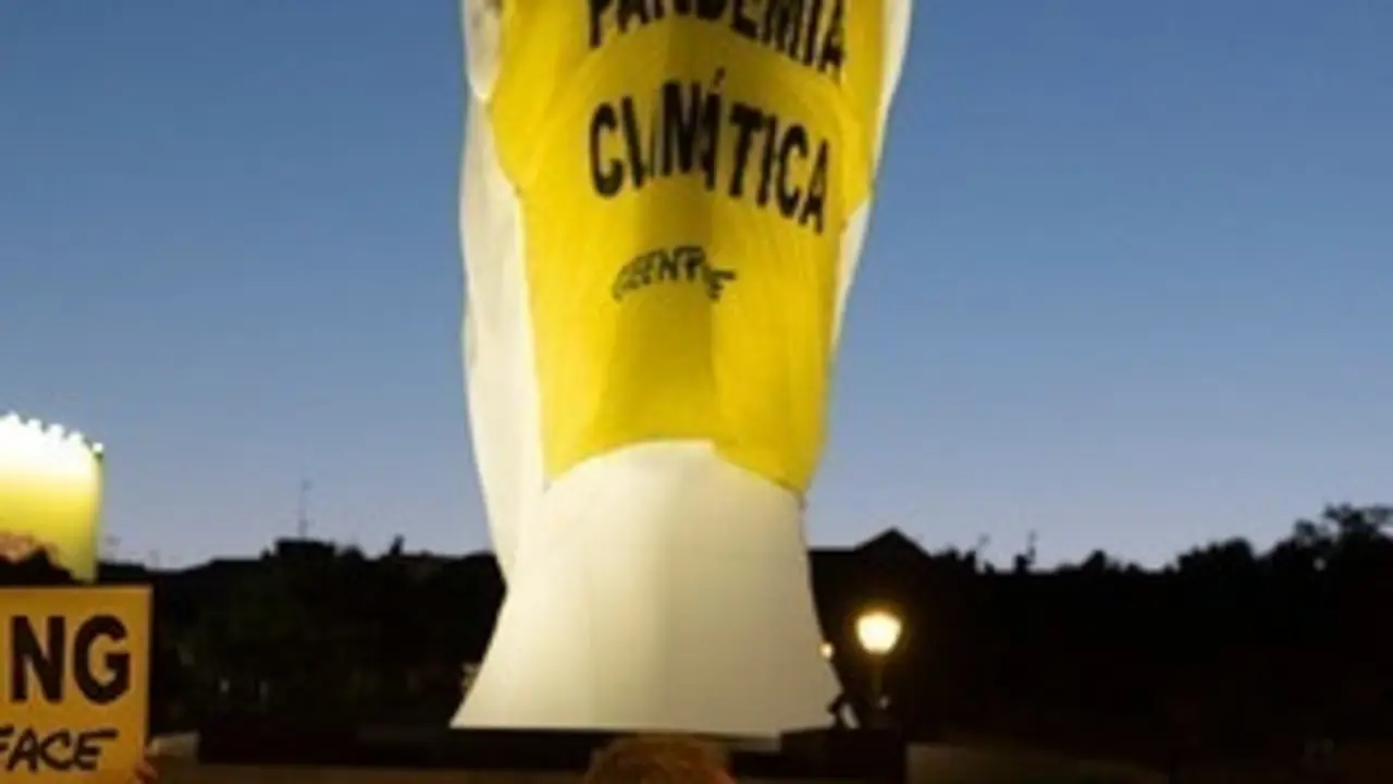 Activistas de Greenpeace han colocado una mascarilla giganteen una escultura de la plaza de Col&oacute;n (Madrid) en la que se lee "Pandemia Clim&aacute;tica".