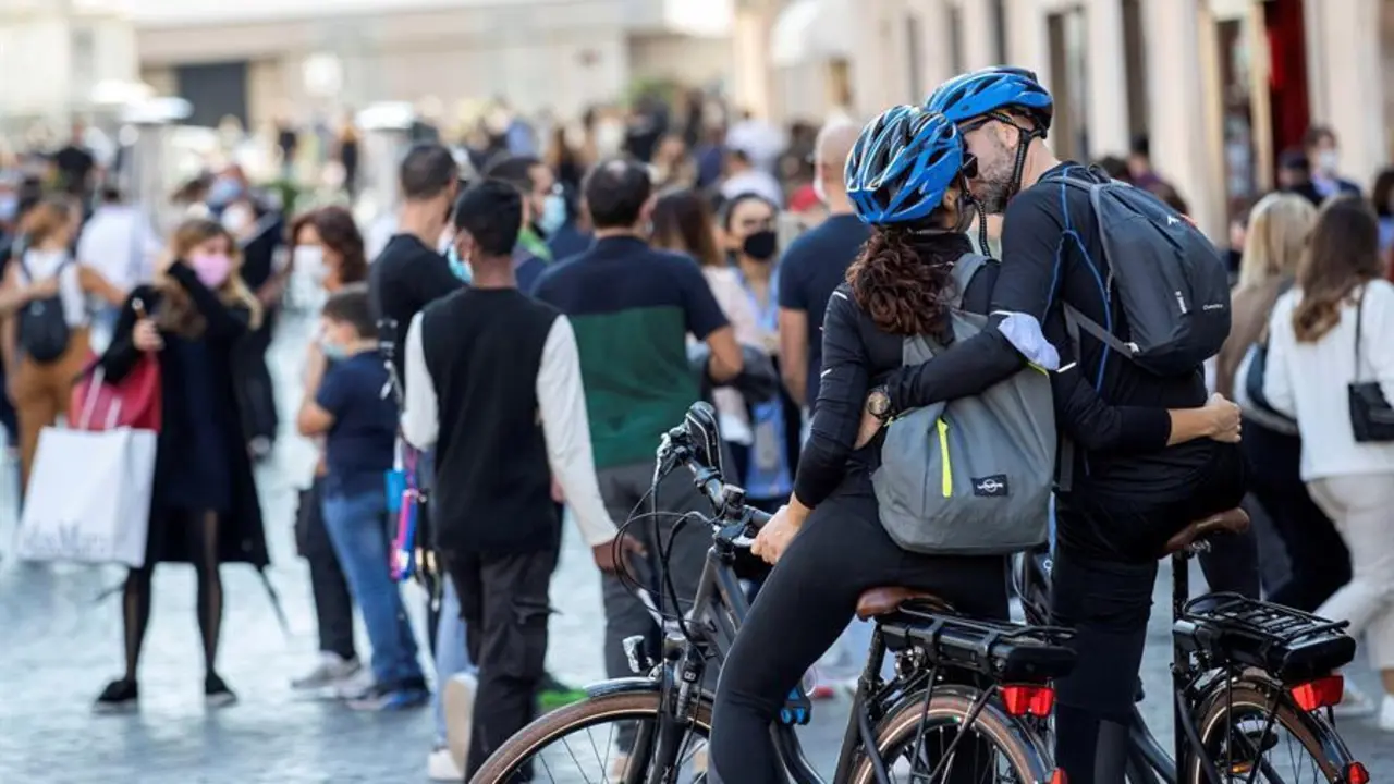 Una pareja se besa mientras centenares de turistas con mascarilla pasean por Roma. EFE/Massimo Percossi