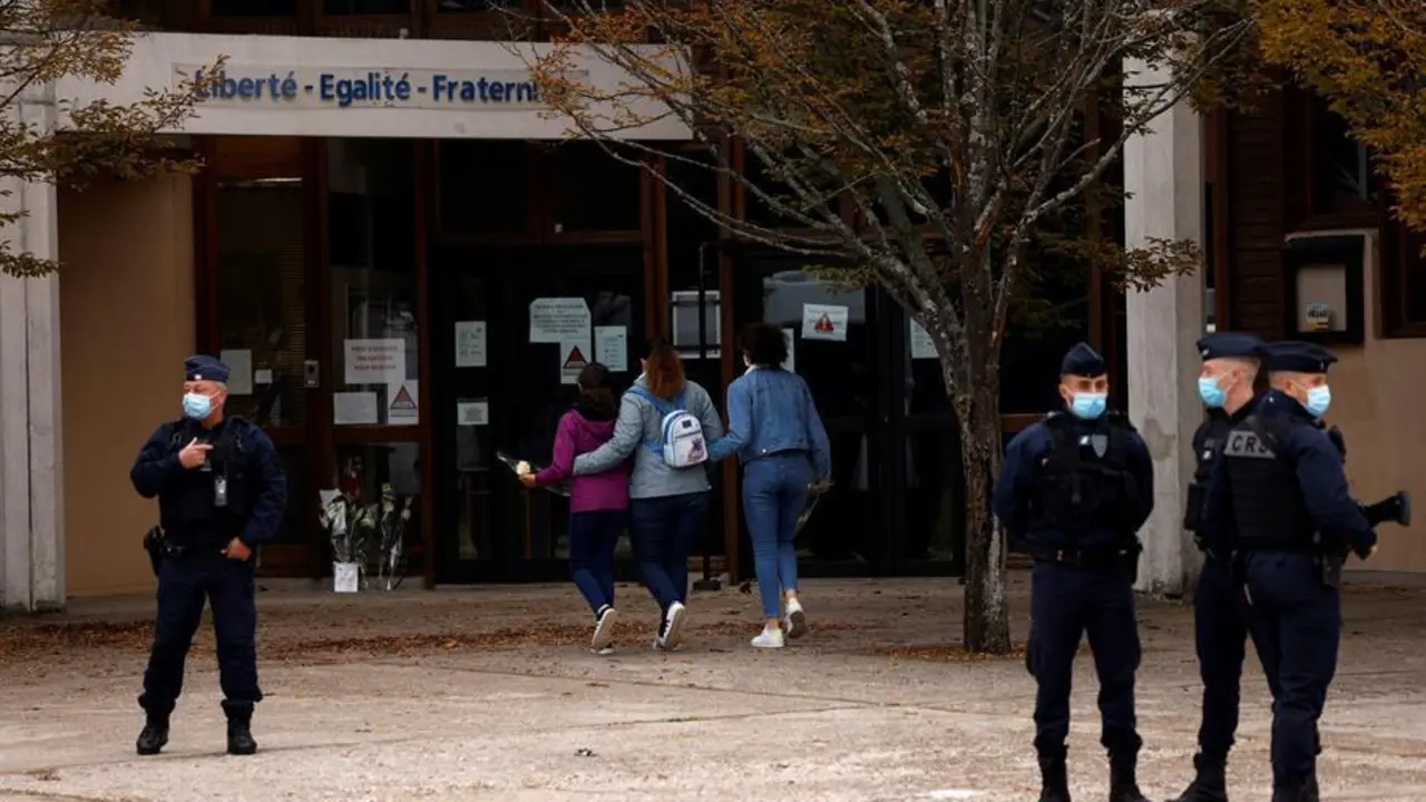 Los adolescentes llegan a depositar flores frente a la escuela secundaria Bois d'Aulne para presentar sus respetos despu&eacute;s del asesinato de un maestro en Conflans Saint-Honorine, en las afueras de Par&iacute;s. / EFE