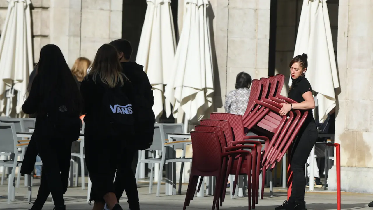 Una joven dependienta prepara las sillas y mesas para atender a los clientes de Santander. / Alerta