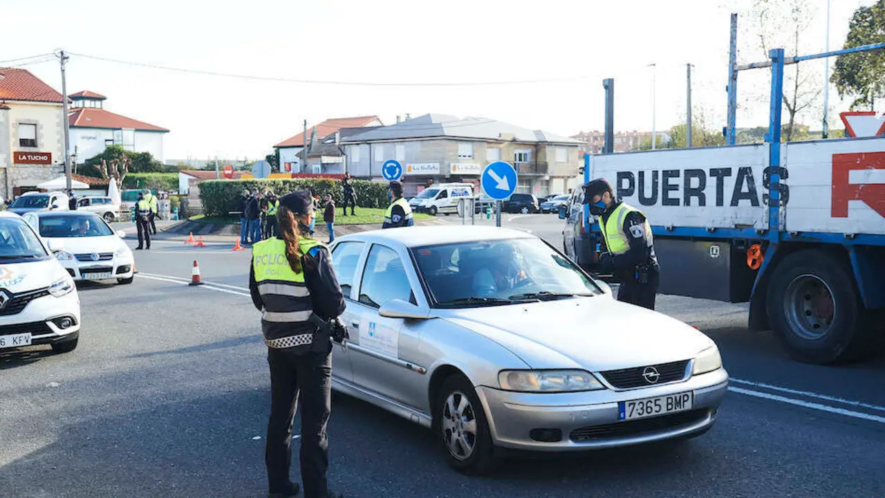 Un ciudadano con su veh&iacute;culo para junto al agente en un control realizado hoy en Corb&aacute;n, Santander. / ALERTA